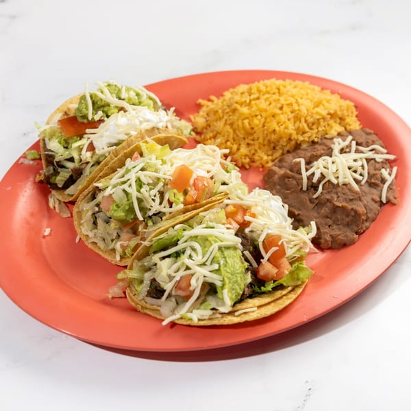 Three De Pasada Mexican tacos with rice and refried beans on a red plate.