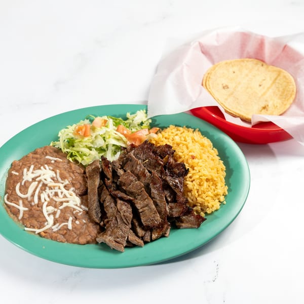De Pasada's carne asada plate with rice, beans, salad, and a side of tortillas.